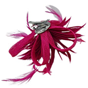 Broche-tocado de plumas en color fucsia . Mide 15 cm x 12 cm aproximadamente. En la parte trasera lleva metal plateado con alfiler para usarlo como broche y una horquilla para lucirlo en el pelo como un tocado. También puede lucirse decorando un bolso o un sombrero.