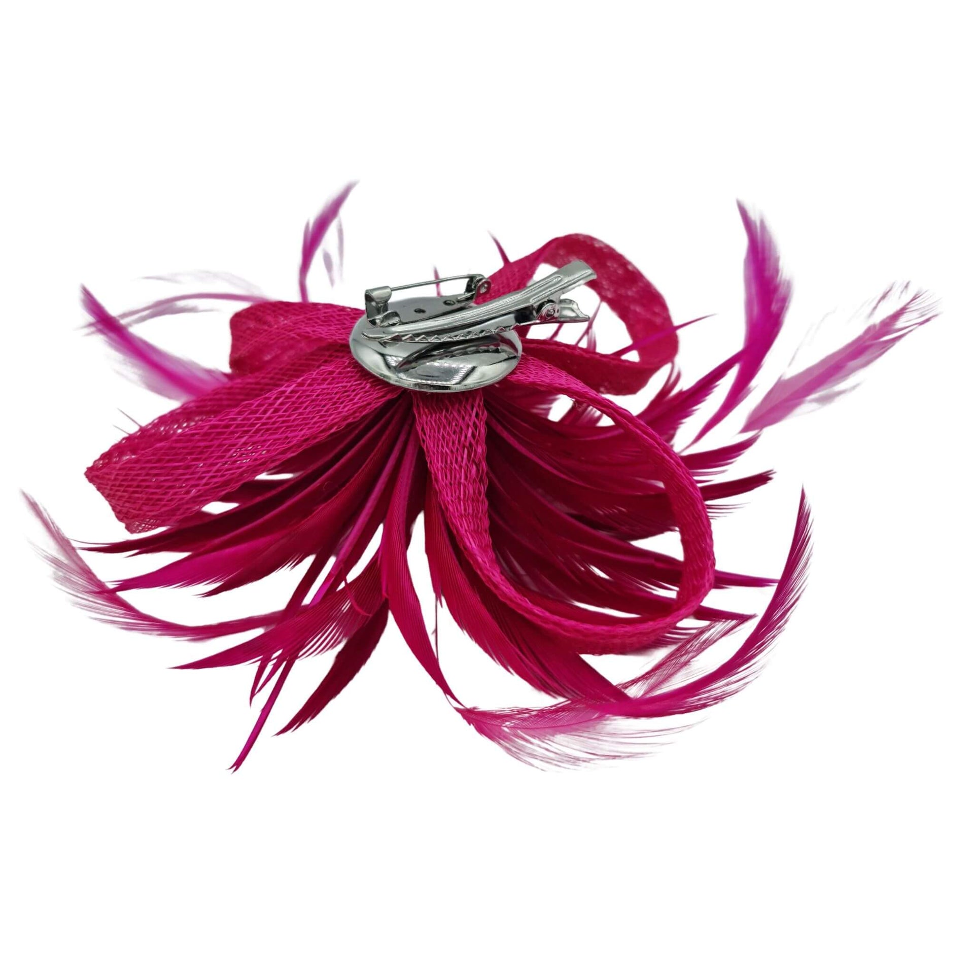 Broche-tocado de plumas en color fucsia . Mide 15 cm x 12 cm aproximadamente. En la parte trasera lleva metal plateado con alfiler para usarlo como broche y una horquilla para lucirlo en el pelo como un tocado. También puede lucirse decorando un bolso o un sombrero.