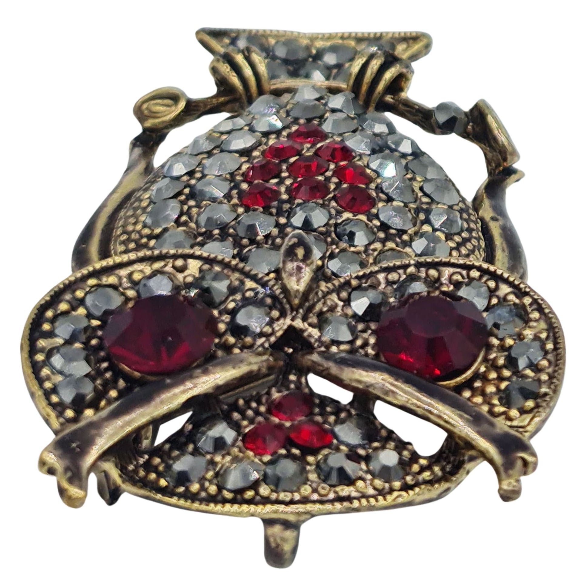 Broche buho colgante de metal dorado y brillantes de strass en color rojo. Trasera en color oro viejo con alfiler y seguro. Además del alfiler habitual, lleva una pieza que permite usarlo como colgante. Mide 6 cm de largo x 3 cm de ancho.