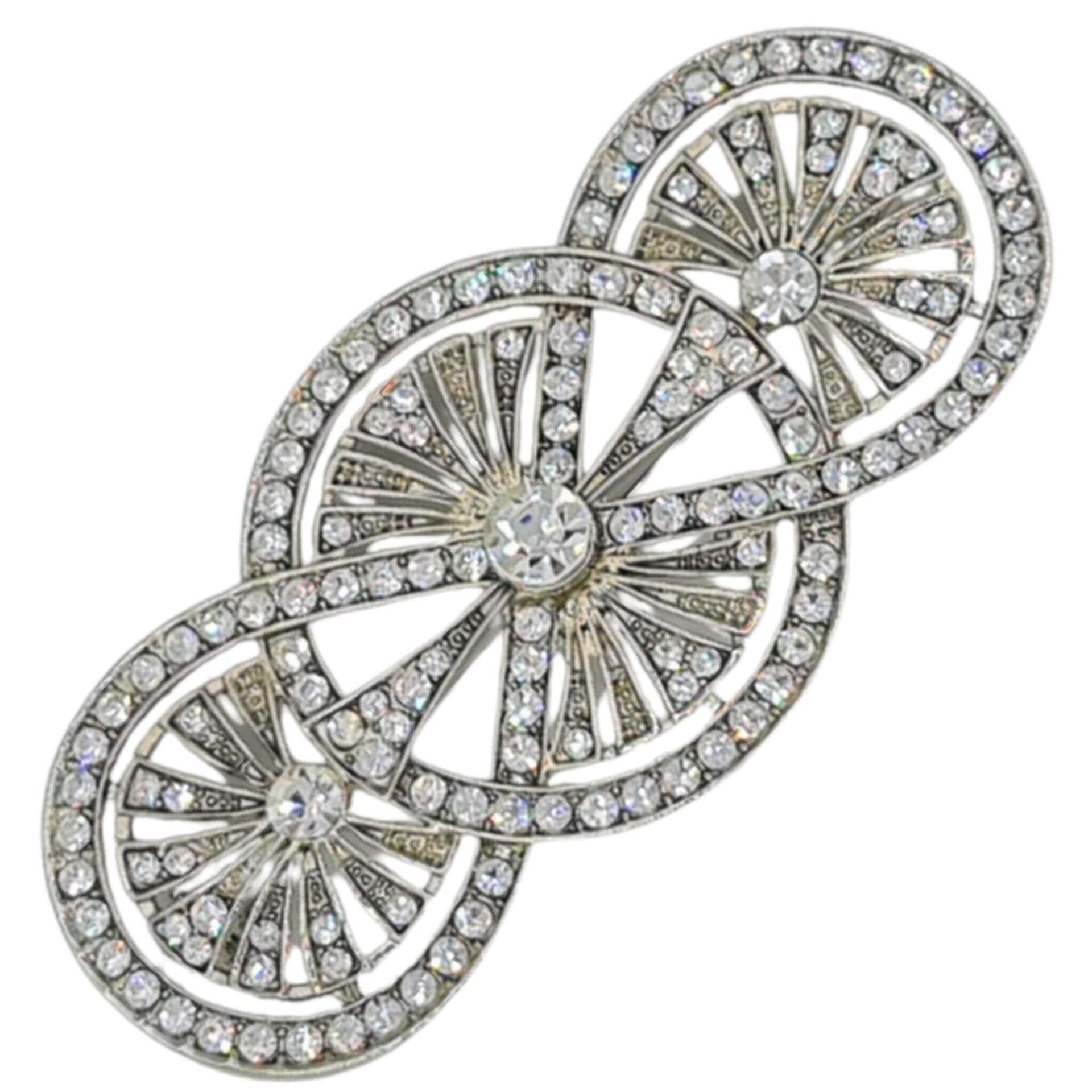 Broche alargado en metal plateado y brillantes de strass en color blanco. Mide 8 cm de largo por 4 cm de ancho. El alfiler trasero es de 7 cm con cierre de seguridad. Un complemento ideal para lucir como broche sobre la ropa, un bolso, un sombrero o un collar.