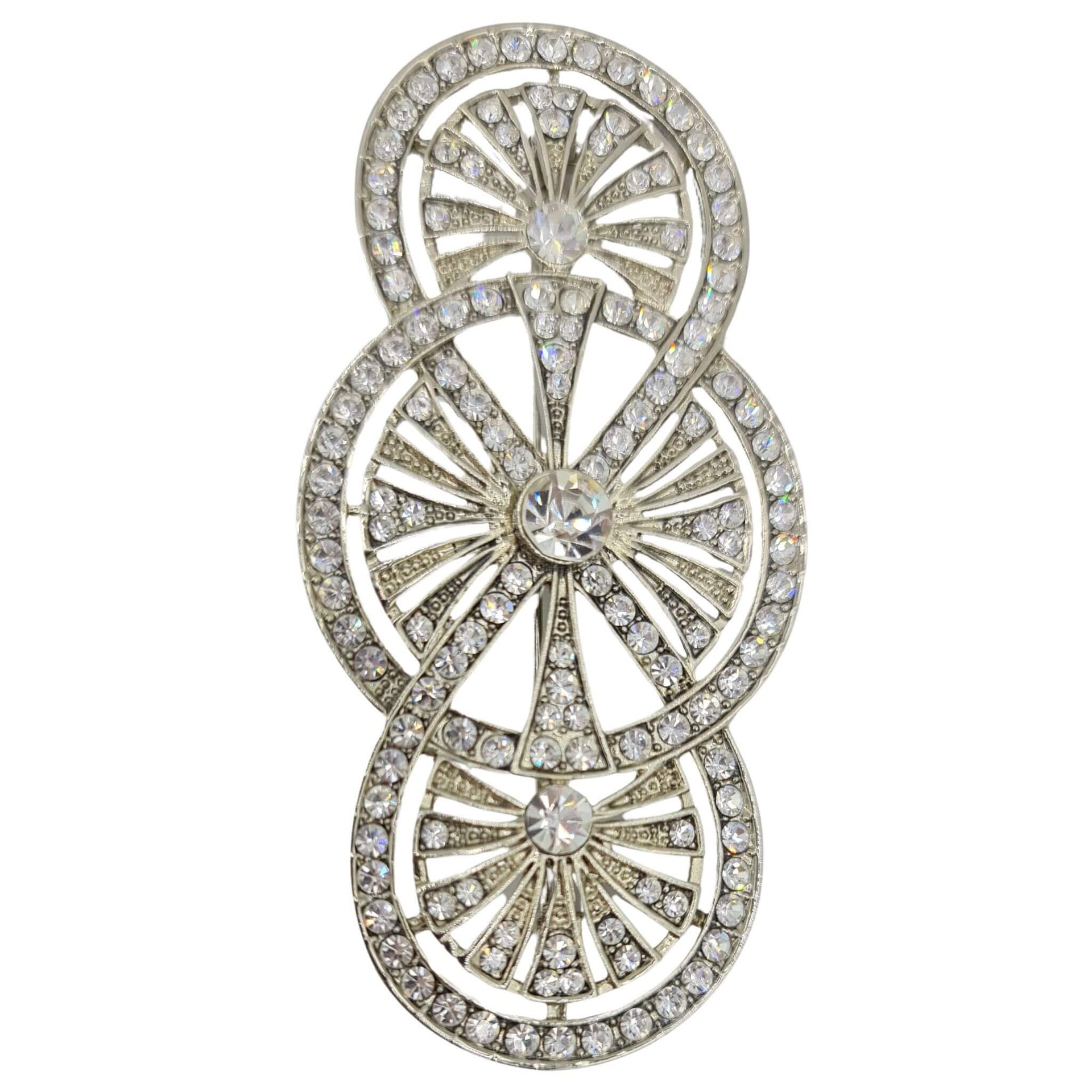 Broche alargado en metal plateado y brillantes de strass en color blanco. Mide 8 cm de largo por 4 cm de ancho. El alfiler trasero es de 7 cm con cierre de seguridad. Un complemento ideal para lucir como broche sobre la ropa, un bolso, un sombrero o un collar.