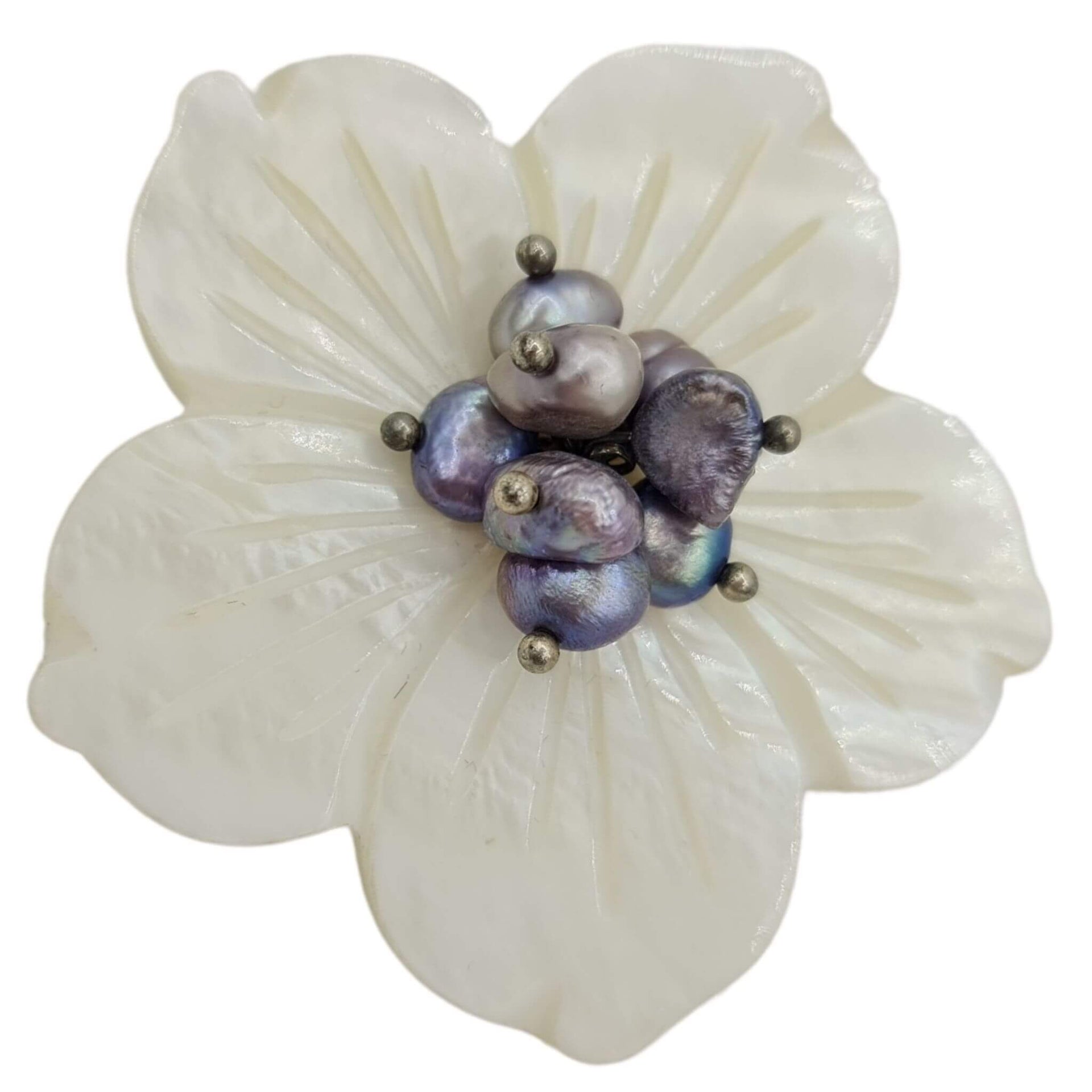 Broche flor nacarada en blanco con central de pequeñas bolitas en color lila. Trasera en metal plateado. Mide 5 cm en su parte más ancha.