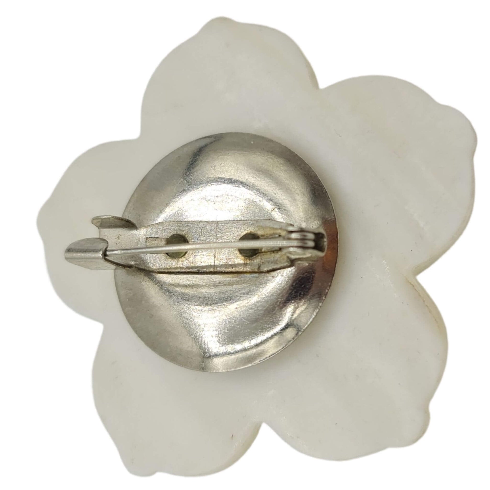 Broche flor nacarada en blanco con central de pequeñas bolitas en color lila. Trasera en metal plateado. Mide 5 cm en su parte más ancha.