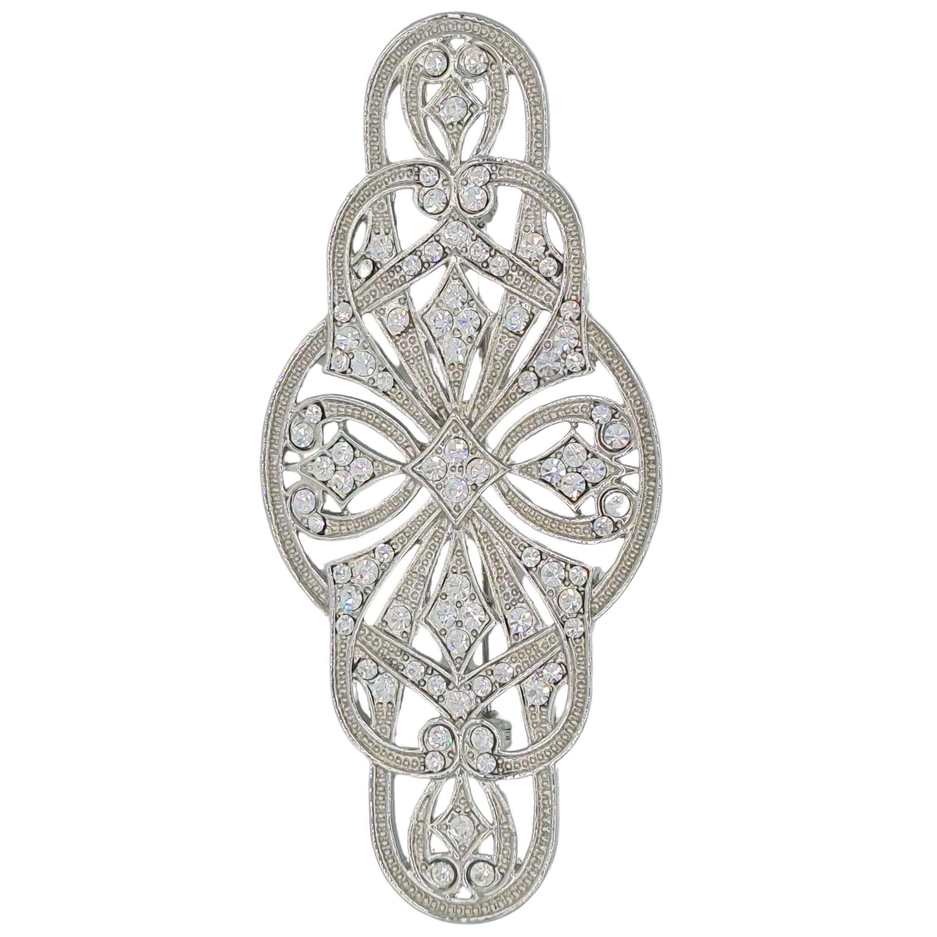 Broche alargado en metal plateado y brillantes de strass en color blanco. Mide 9 cm de largo por 4 cm de ancho. El alfiler trasero es de 6 cm con cierre de seguridad. Un complemento ideal para lucir como broche sobre la ropa, un bolso, un sombrero o un collar.