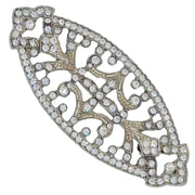 Broche ovalado en forma de pera en metal plateado y brillantes de strass en color blanco. Mide 7 cm de largo por 3 cm de ancho. El alfiler trasero es de 5 cm con cierre de seguridad. Un complemento ideal para lucir como broche sobre la ropa, un bolso, un sombrero o un collar.