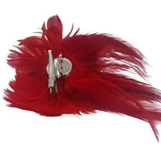 Broche-tocado de plumas en color rojo. Mide 16 cm x 12 cm aproximadamente. En la parte trasera lleva metal plateado con alfiler para usarlo como broche y una horquilla para lucirlo en el pelo como un tocado. También puede lucirse decorando un bolso o un sombrero.