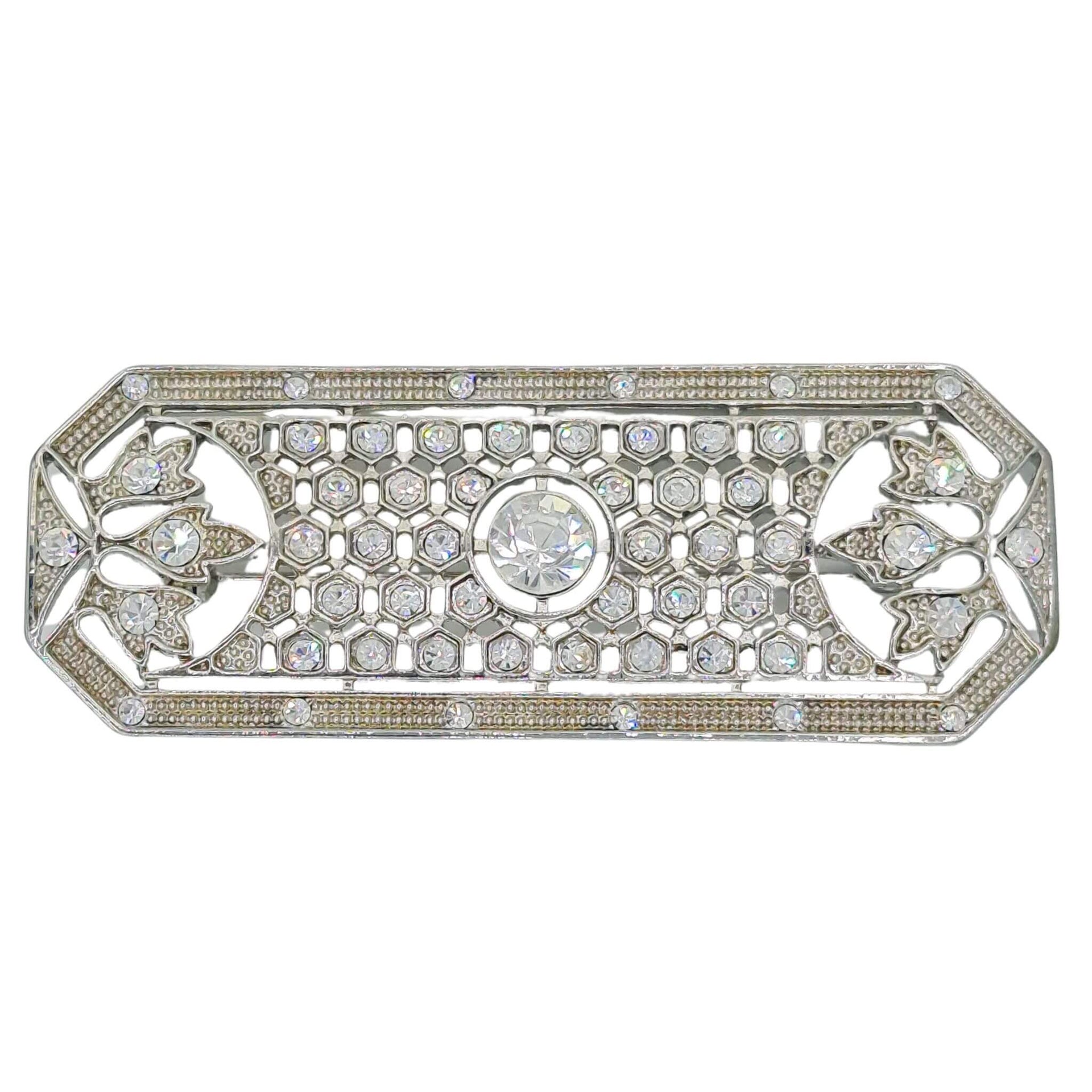 Broche rectangular en metal plateado y brillantes de strass en color blanco. Mide 8 cm de largo por 3 cm de ancho.&nbsp; El alfiler trasero es de 6 cm con cierre de seguridad. Un complemento ideal para lucir como broche sobre la ropa, un bolso, un sombrero o un collar.